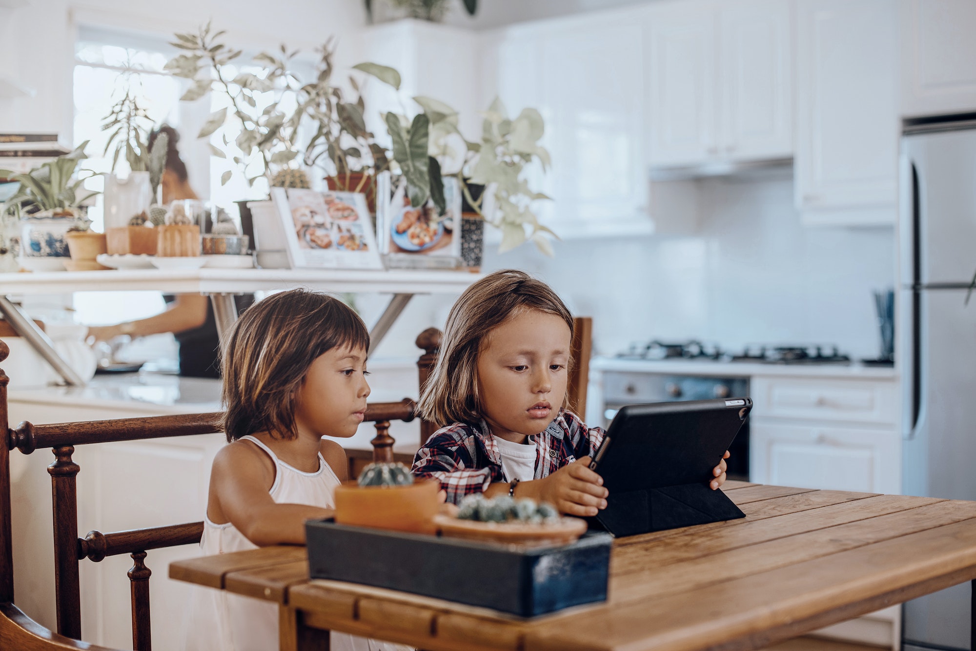 Little kid and his sister use digital tablet together in living room